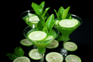 clear cocktail glass with green liquid and sliced lime