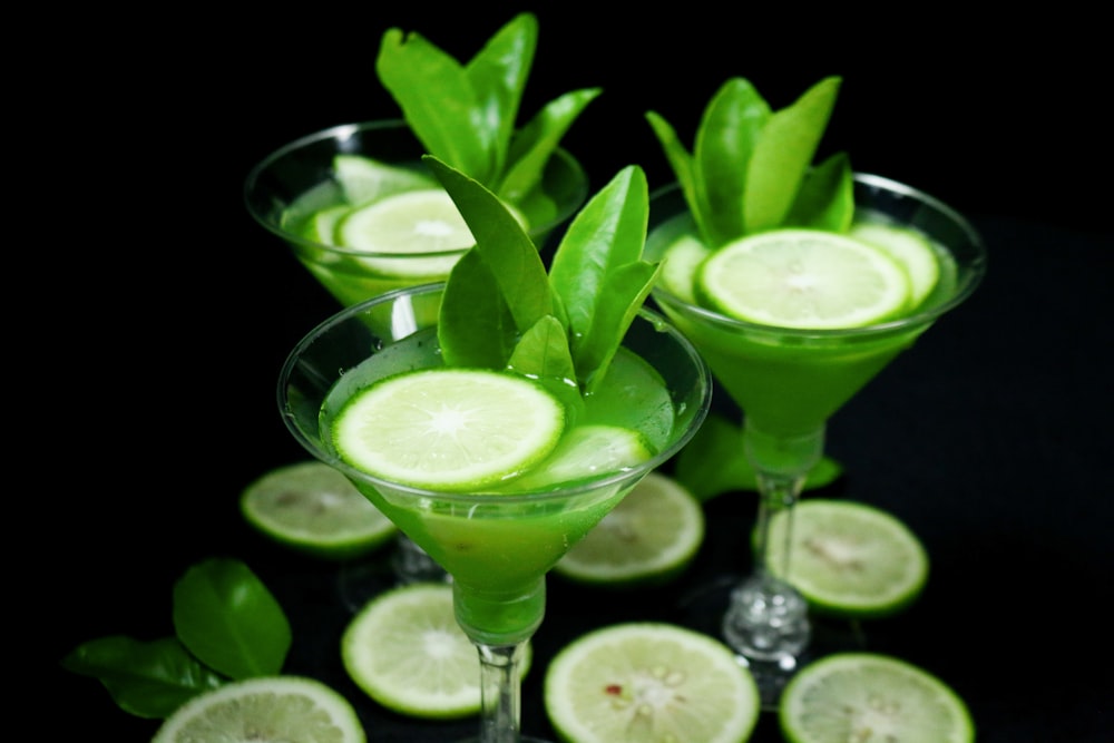 clear cocktail glass with green liquid and sliced lime