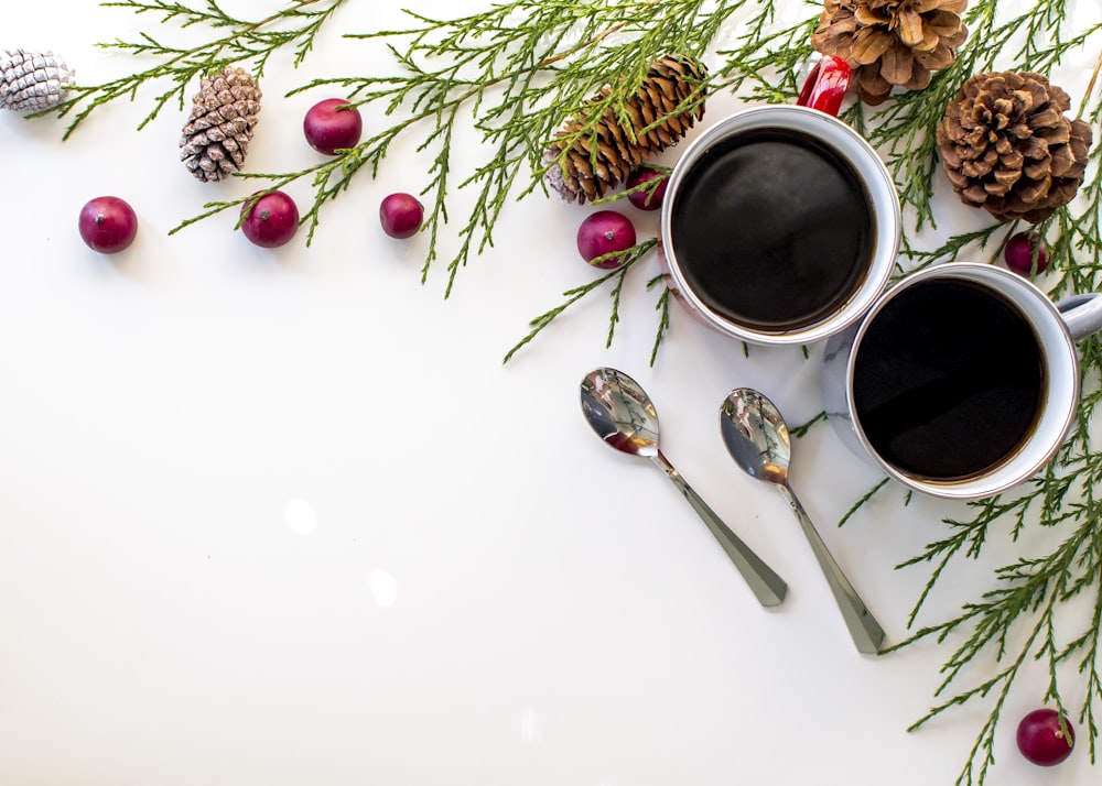 white ceramic mug with coffee beside stainless steel spoon and fork