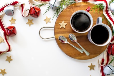 stainless steel fork beside white ceramic mug on brown wooden round plate sleigh bells teams background
