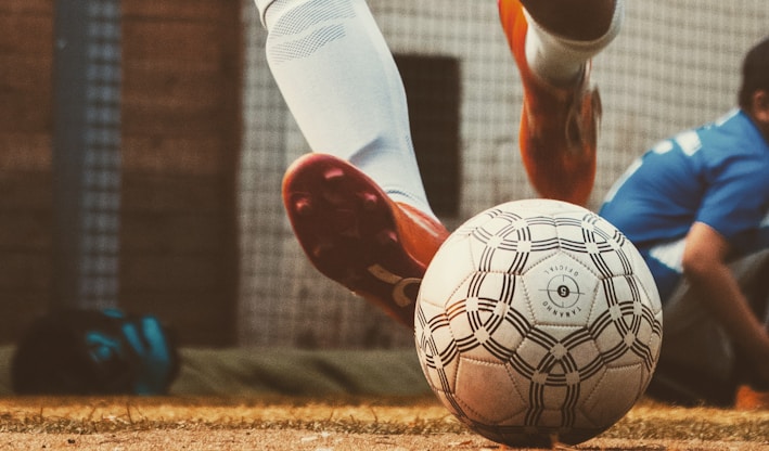 person in white and red soccer jersey kicking soccer ball