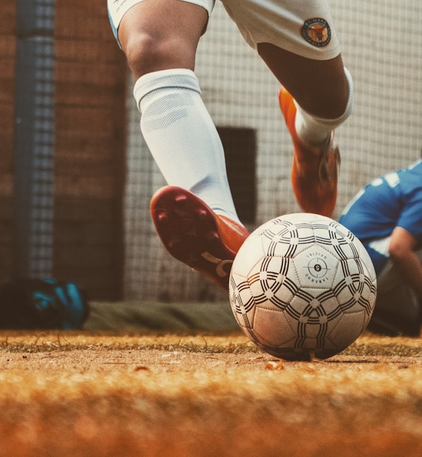 person in white and red soccer jersey kicking soccer ball