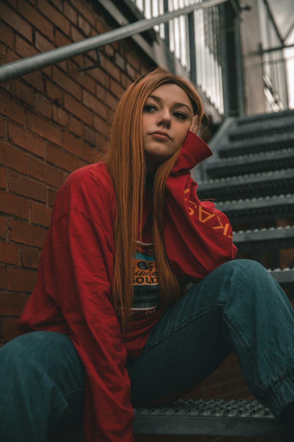 woman in red hoodie and blue denim jeans sitting on stairs