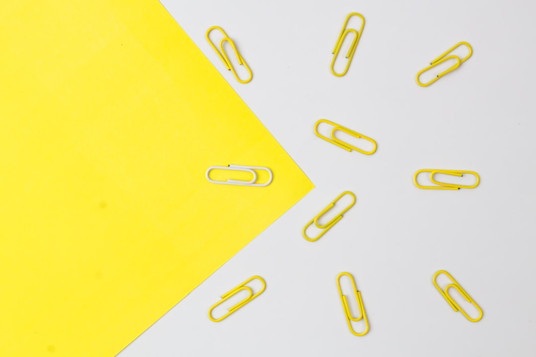 Yellow color paper clips with only a white one isolated on paper background