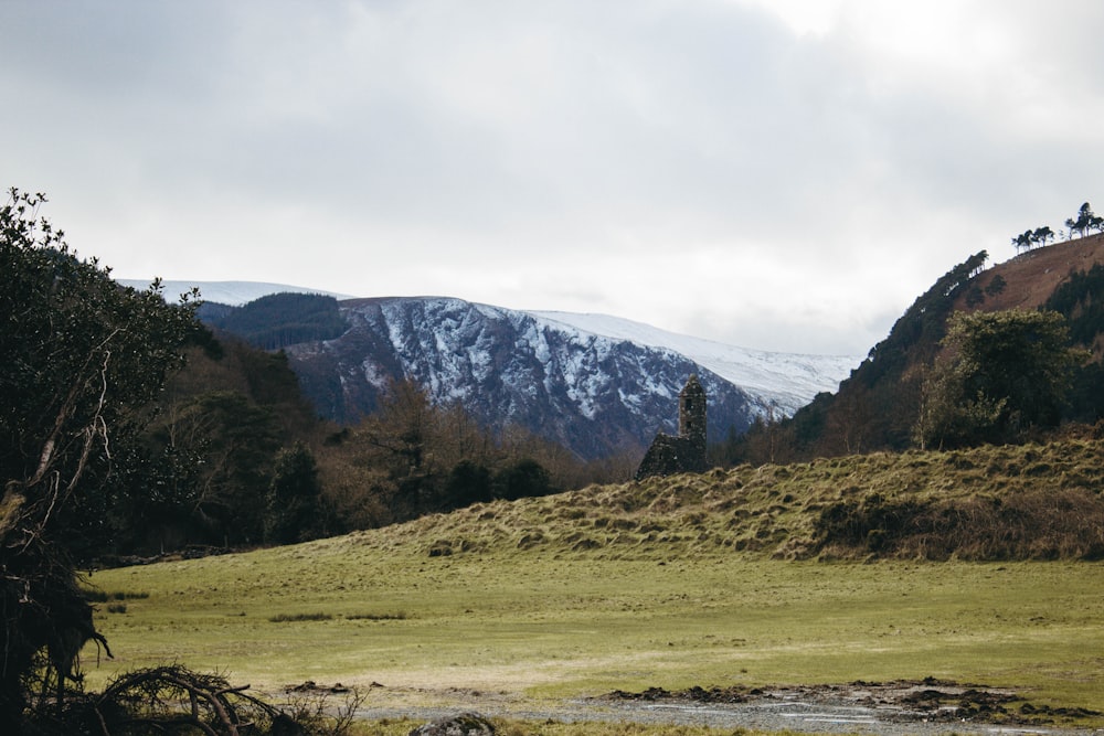 green grass field near mountain under white sky during daytime