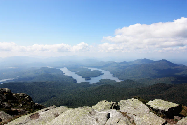 Green Adirondack mountains and a lake under a bright blue sky