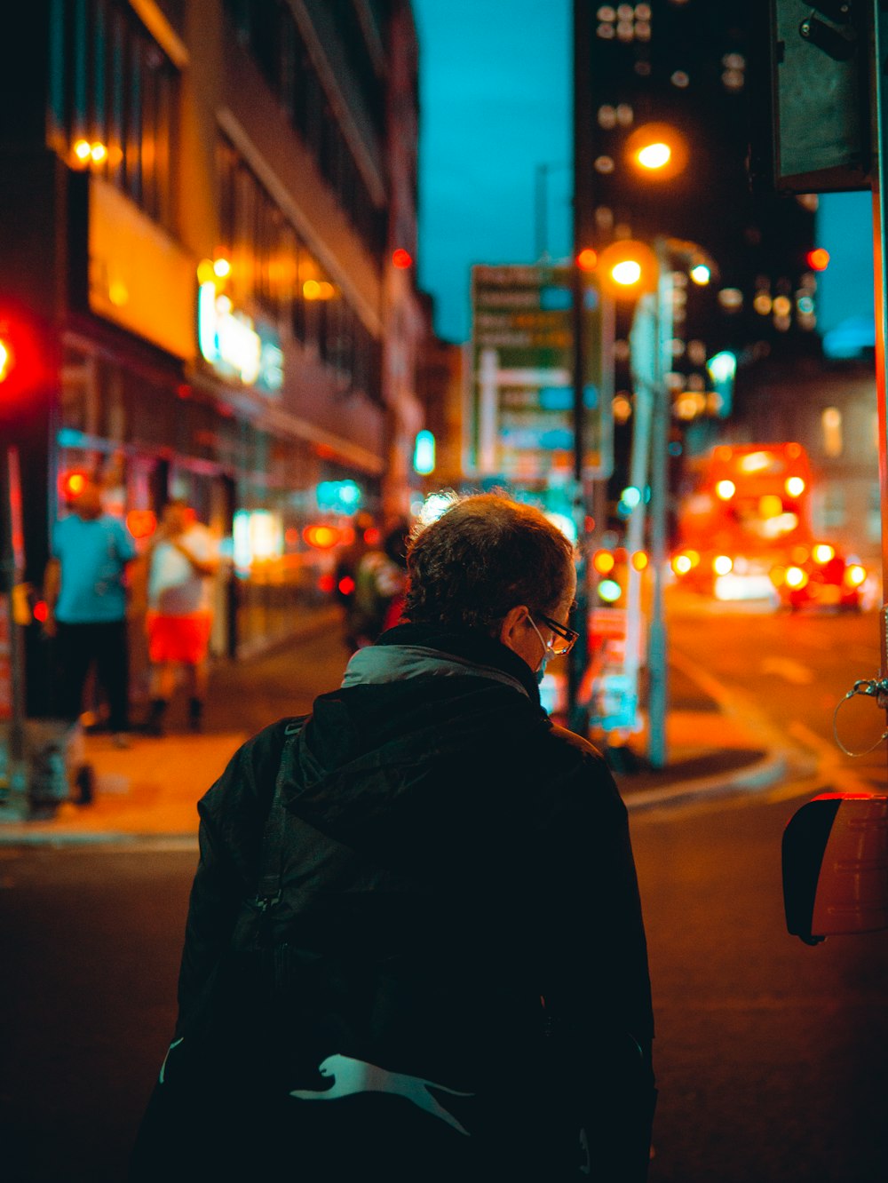 夜間に歩道に立つ黒いジャケットの男
