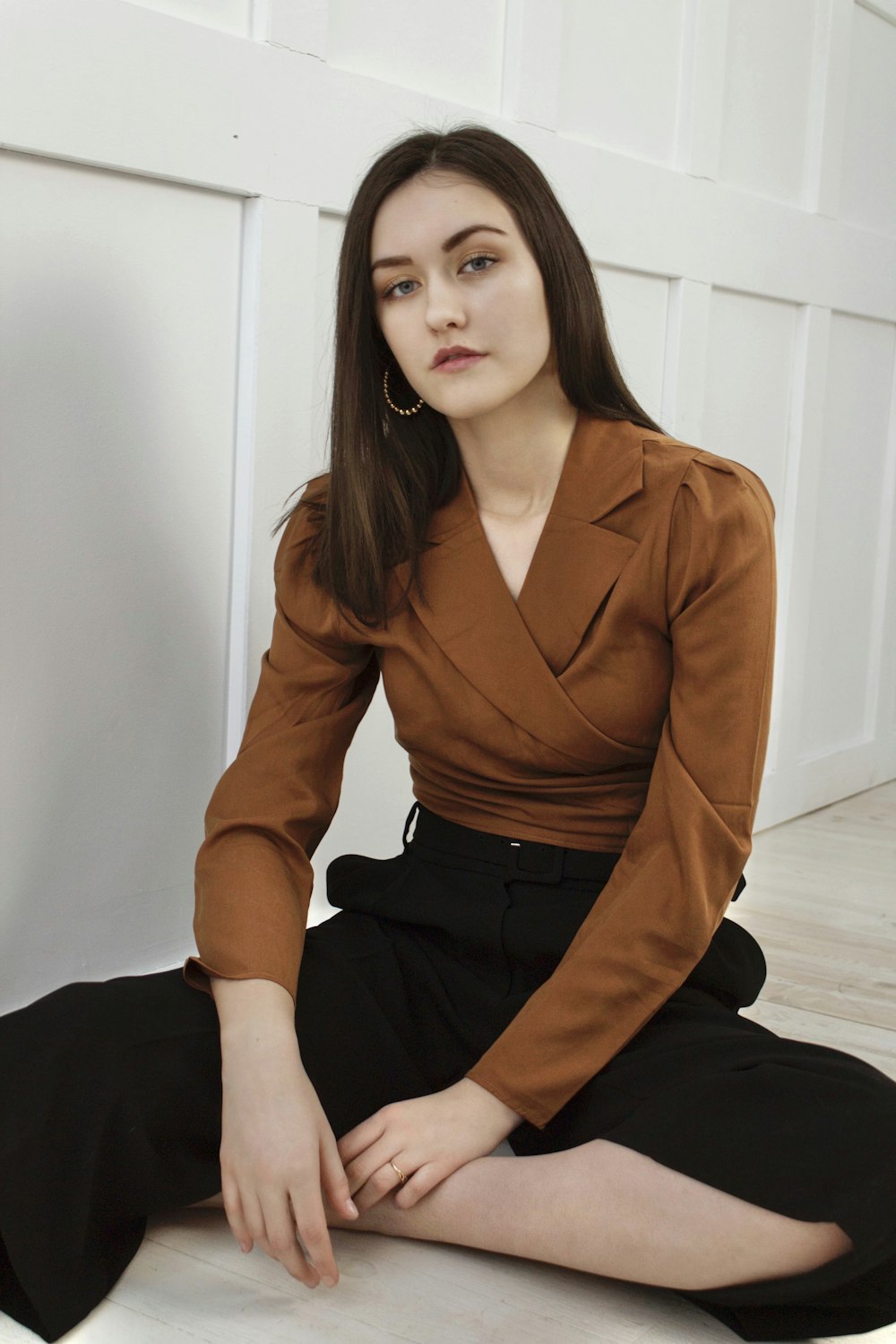 woman in brown blazer and black skirt sitting on white floor