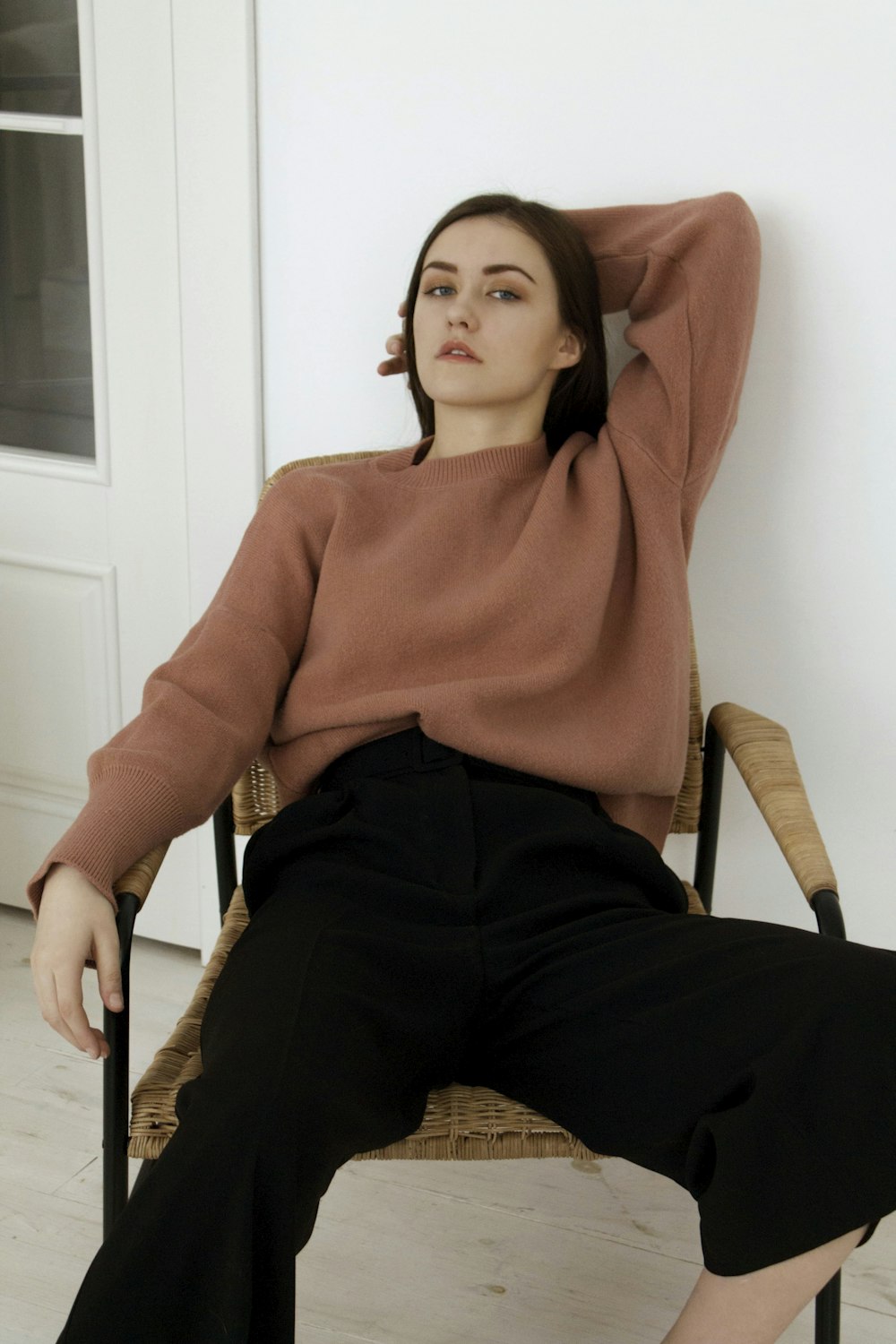 woman in pink sweater sitting on brown wooden armchair