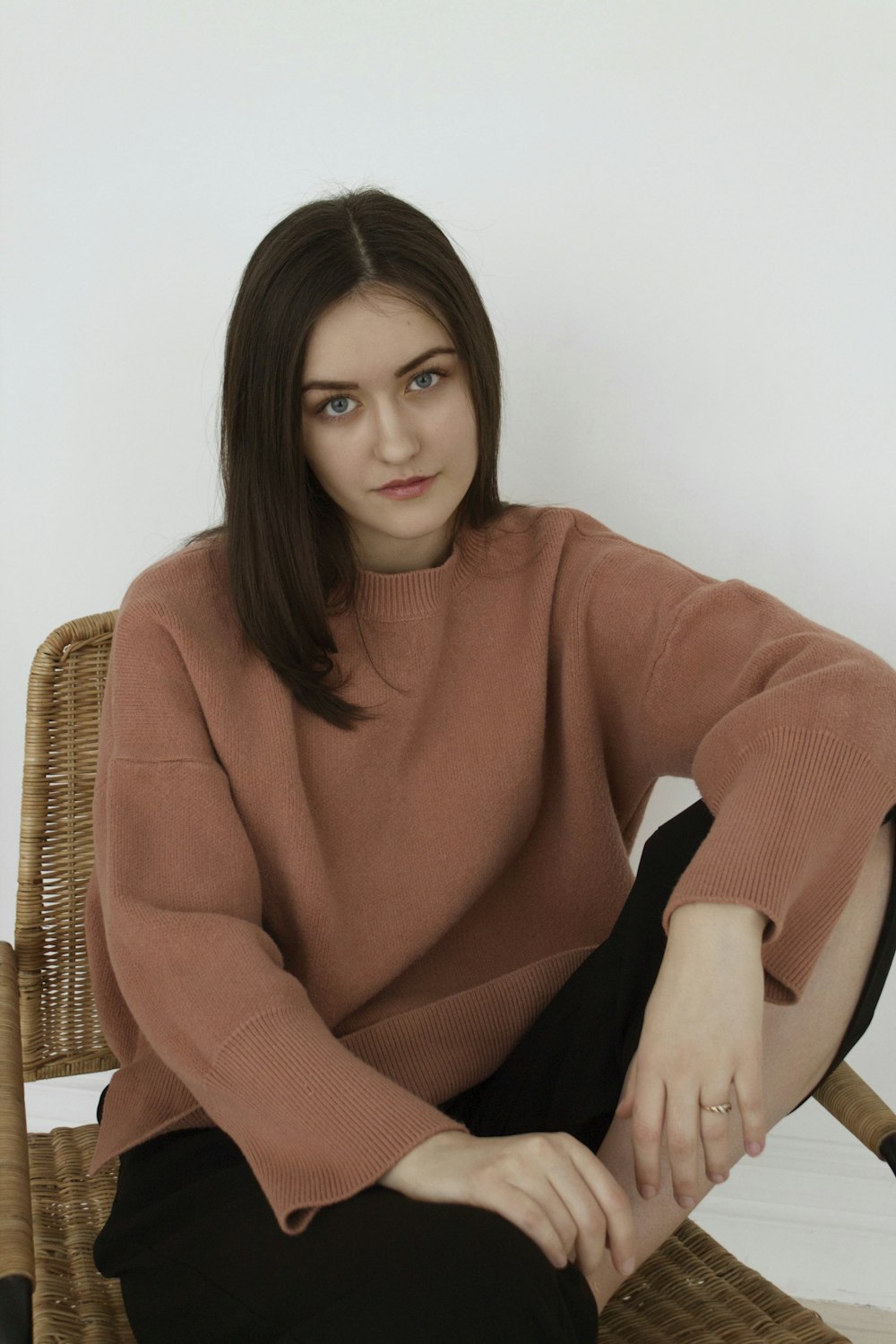 woman in brown turtleneck sweater sitting on brown wicker armchair