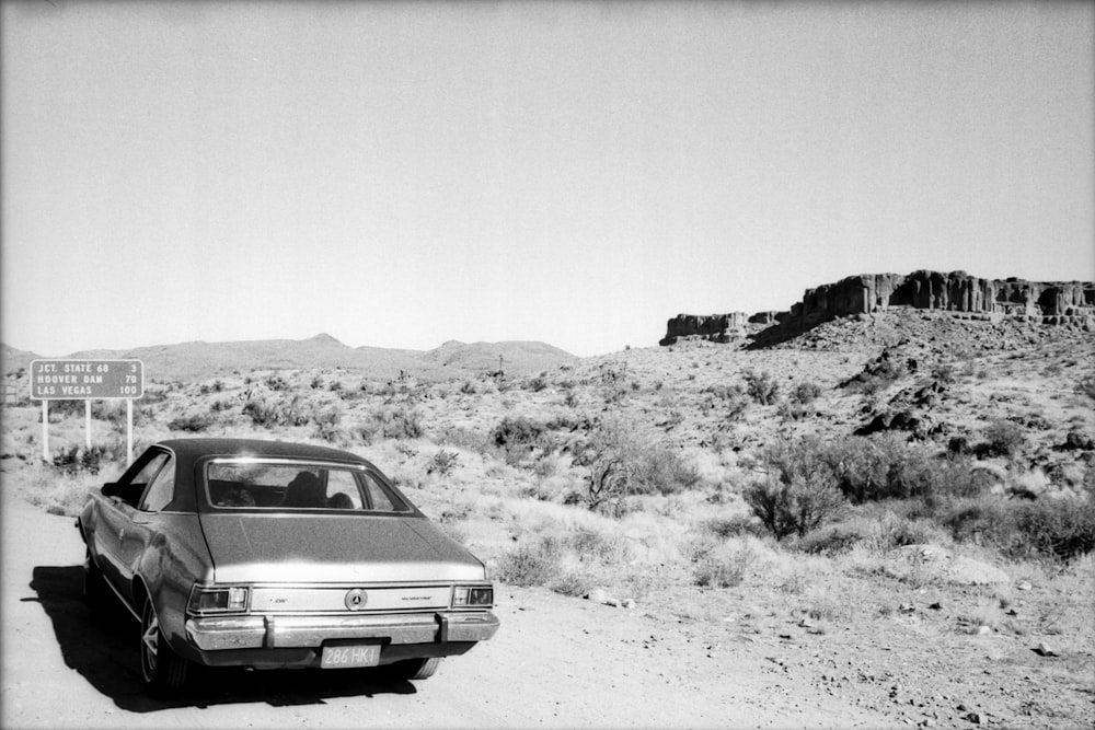 grayscale photo of car on dirt road