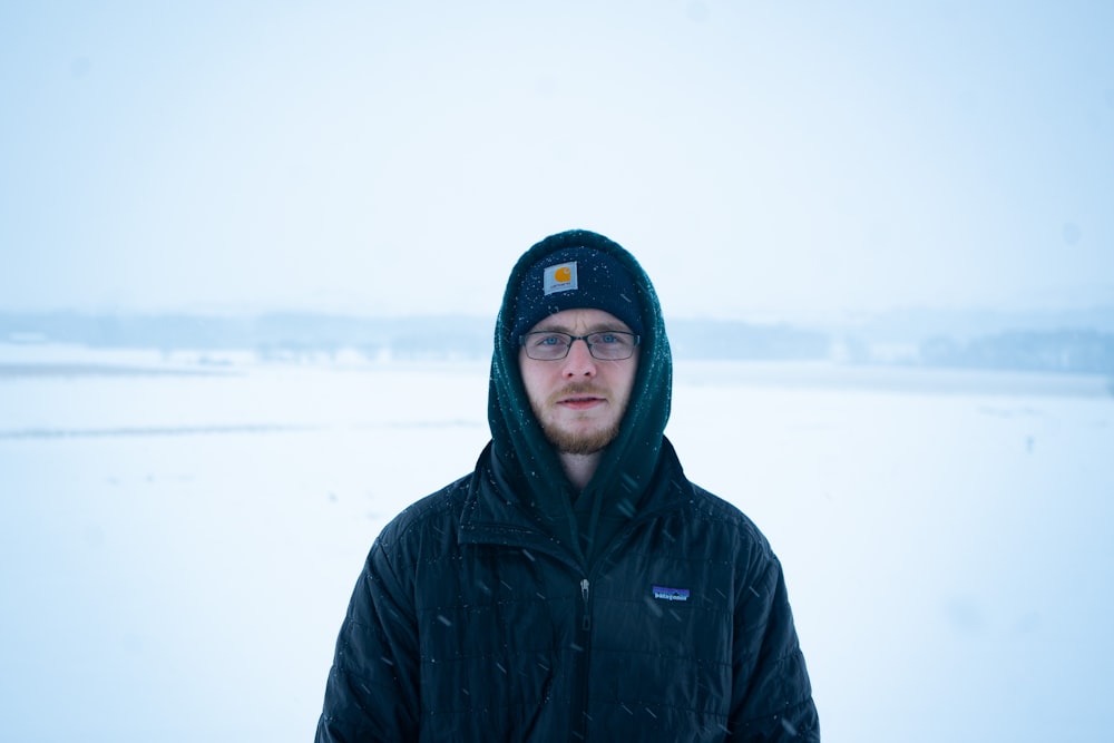 man in black hoodie standing on snow covered ground during daytime