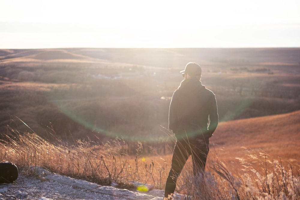 man in black jacket standing on gray dirt road during daytime