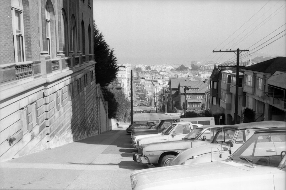 grayscale photo of cars parked beside building