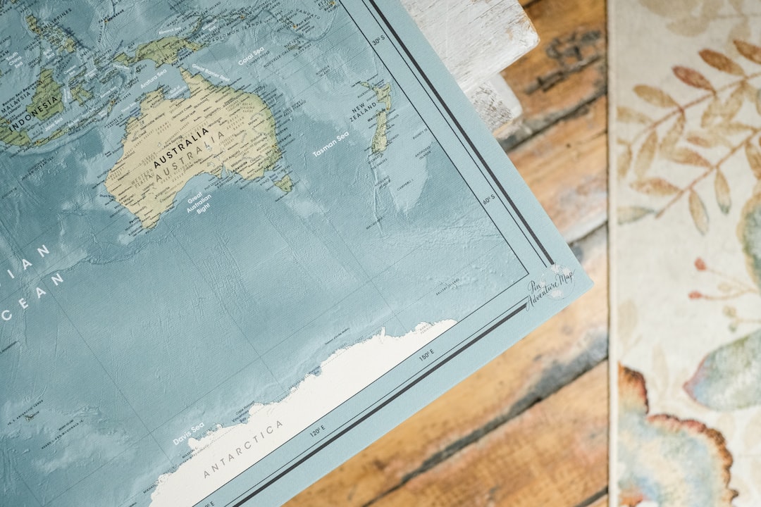 blue and white map on brown wooden table, 📍 World map ("Gulf Stream") with push pins closeup for travel tracking by Pin Adventure Map