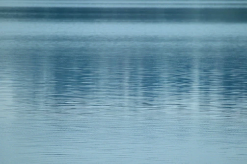 A serene poolside scene with gentle ripples reflecting soft blue and sandy tones.