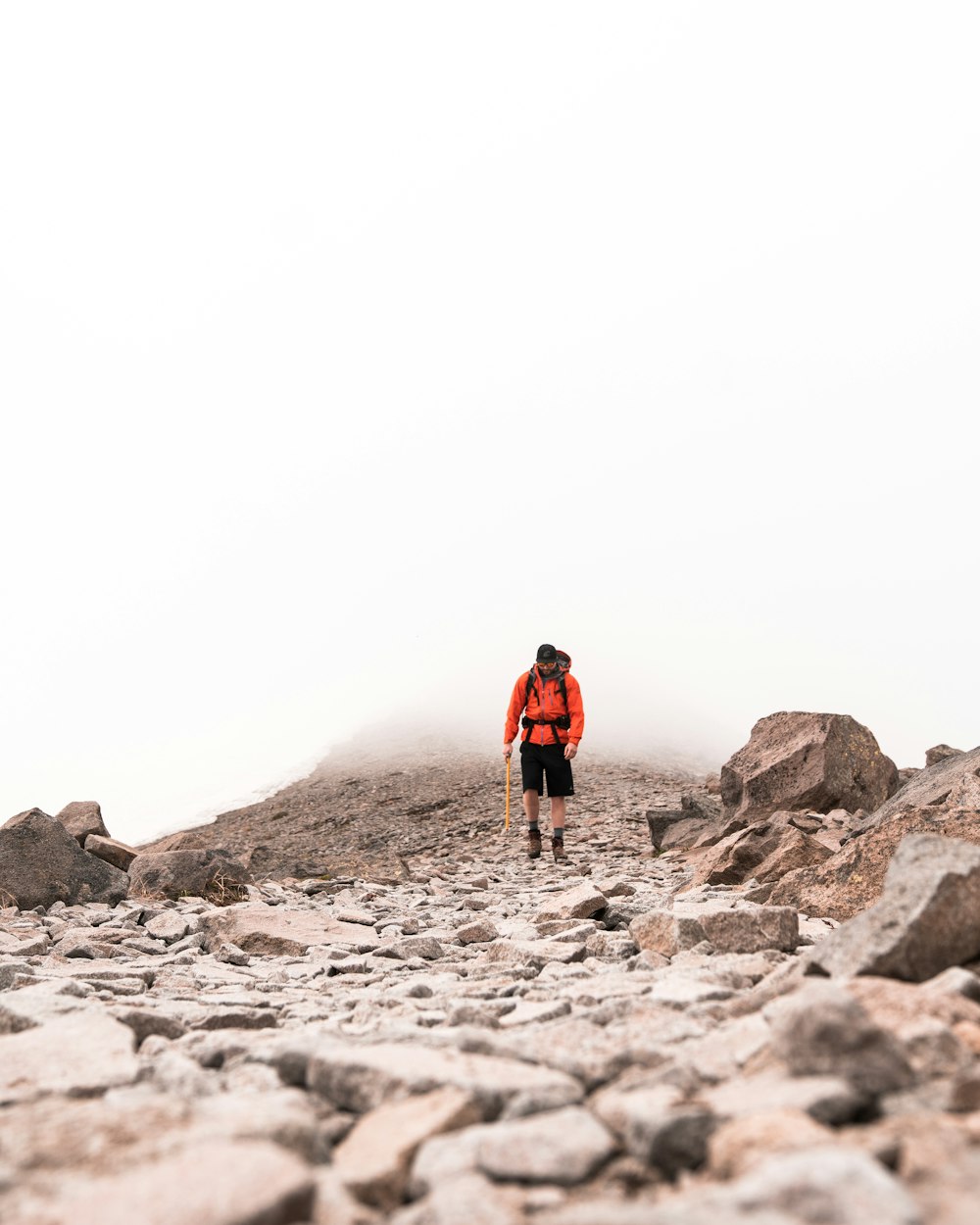 man in red jacket standing on gray rock