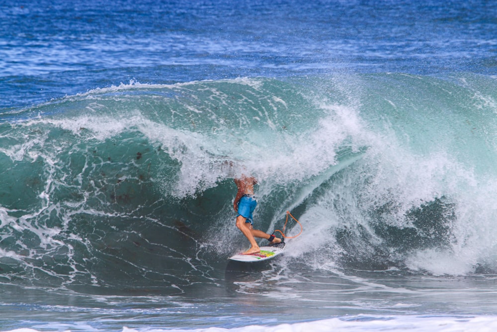 man in blue and red wetsuit surfing on sea waves during daytime