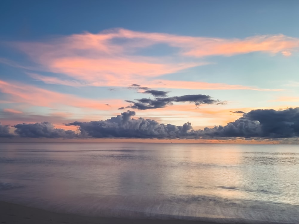 body of water under cloudy sky during sunset