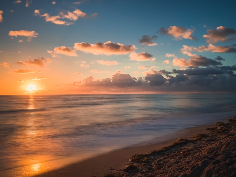 body of water under cloudy sky during sunset