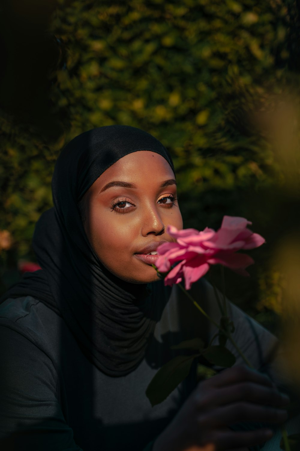 분홍색 꽃을 들고 검은 히잡을 쓴 여자