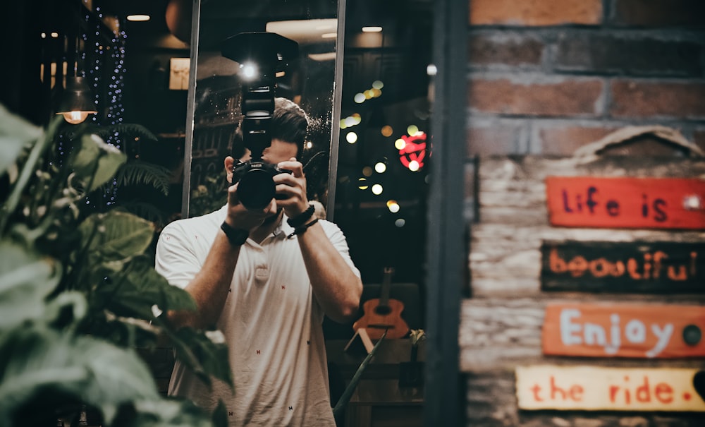 Hombre con camisa blanca abotonada sosteniendo una cámara DSLR negra