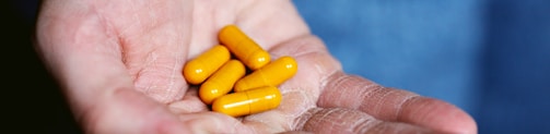 yellow medication pill on persons hand