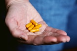 yellow medication pill on persons hand