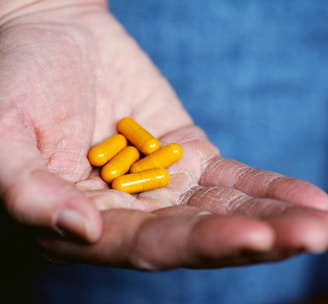 yellow medication pill on persons hand