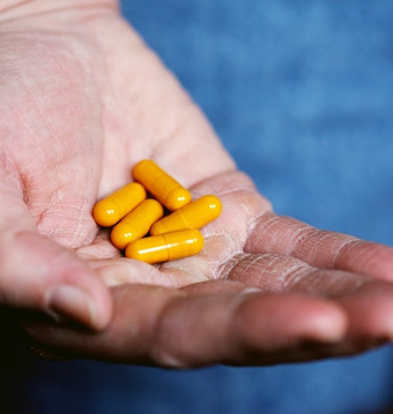 yellow medication pill on persons hand