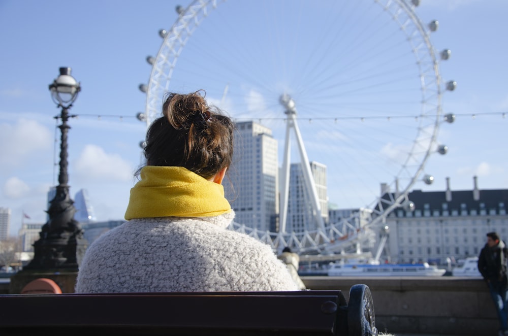 woman in white knit sweater looking at ferris wheel during daytime