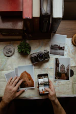 Close-up of hands arranging old photographs and handwritten notes on a wooden table.