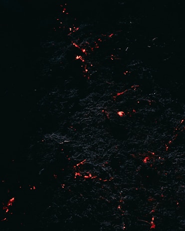 Pixel art of a glowing lava river winding through a dark cavern, with ember sparks floating above.