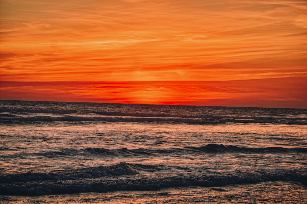 ocean waves crashing on shore during sunset