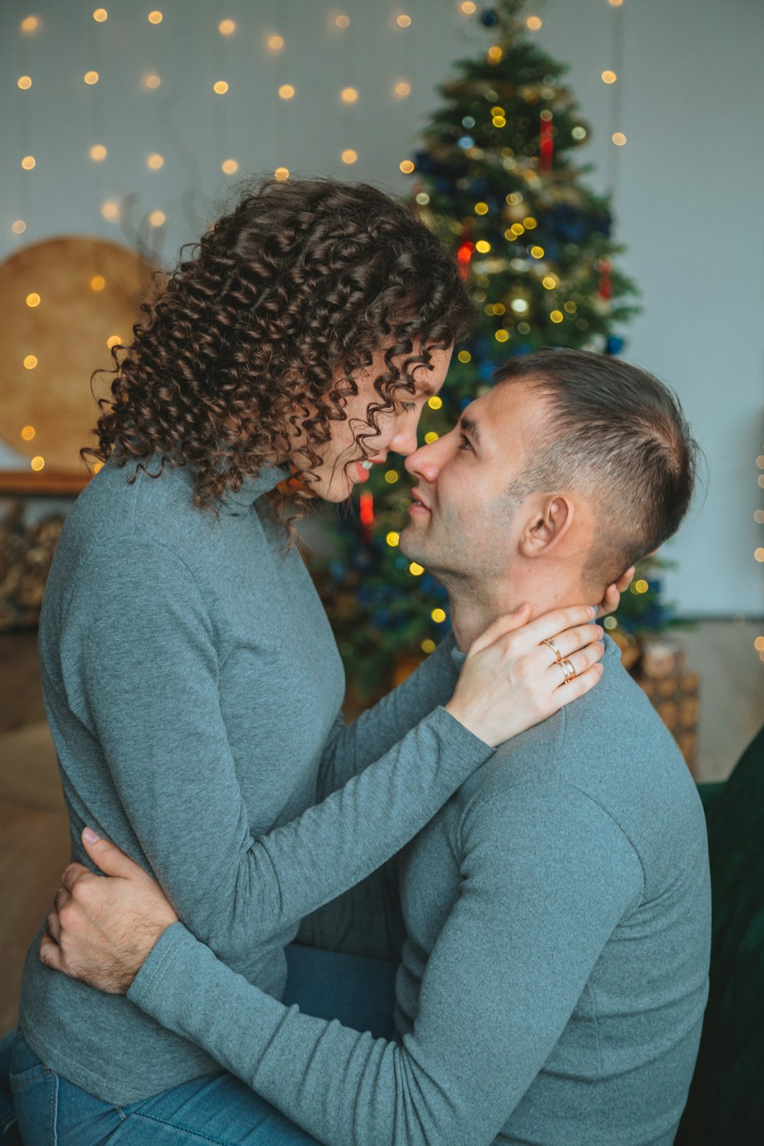 man in gray sweater kissing woman in blue sweater