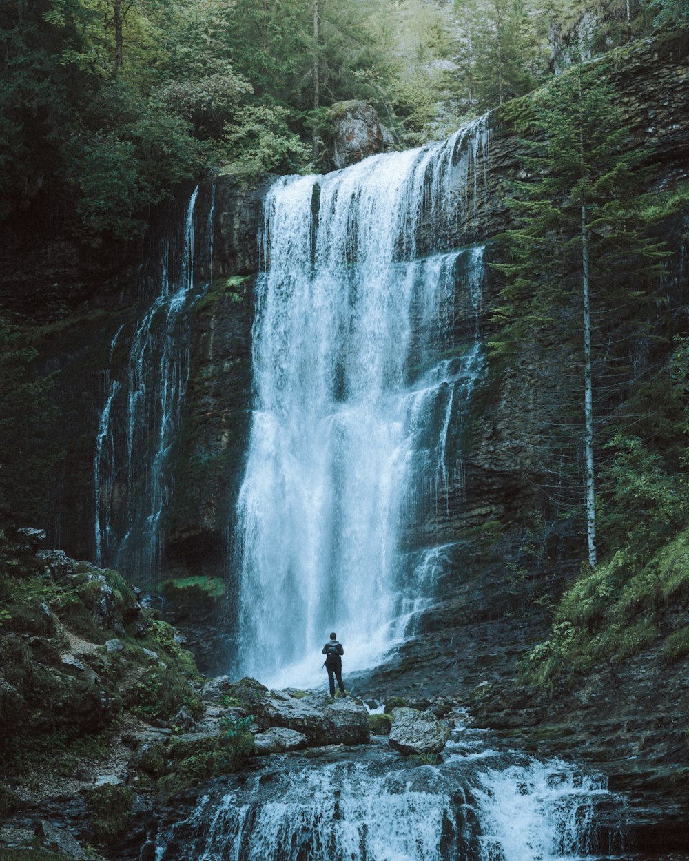 pessoa em pé na rocha perto de cachoeiras durante o dia