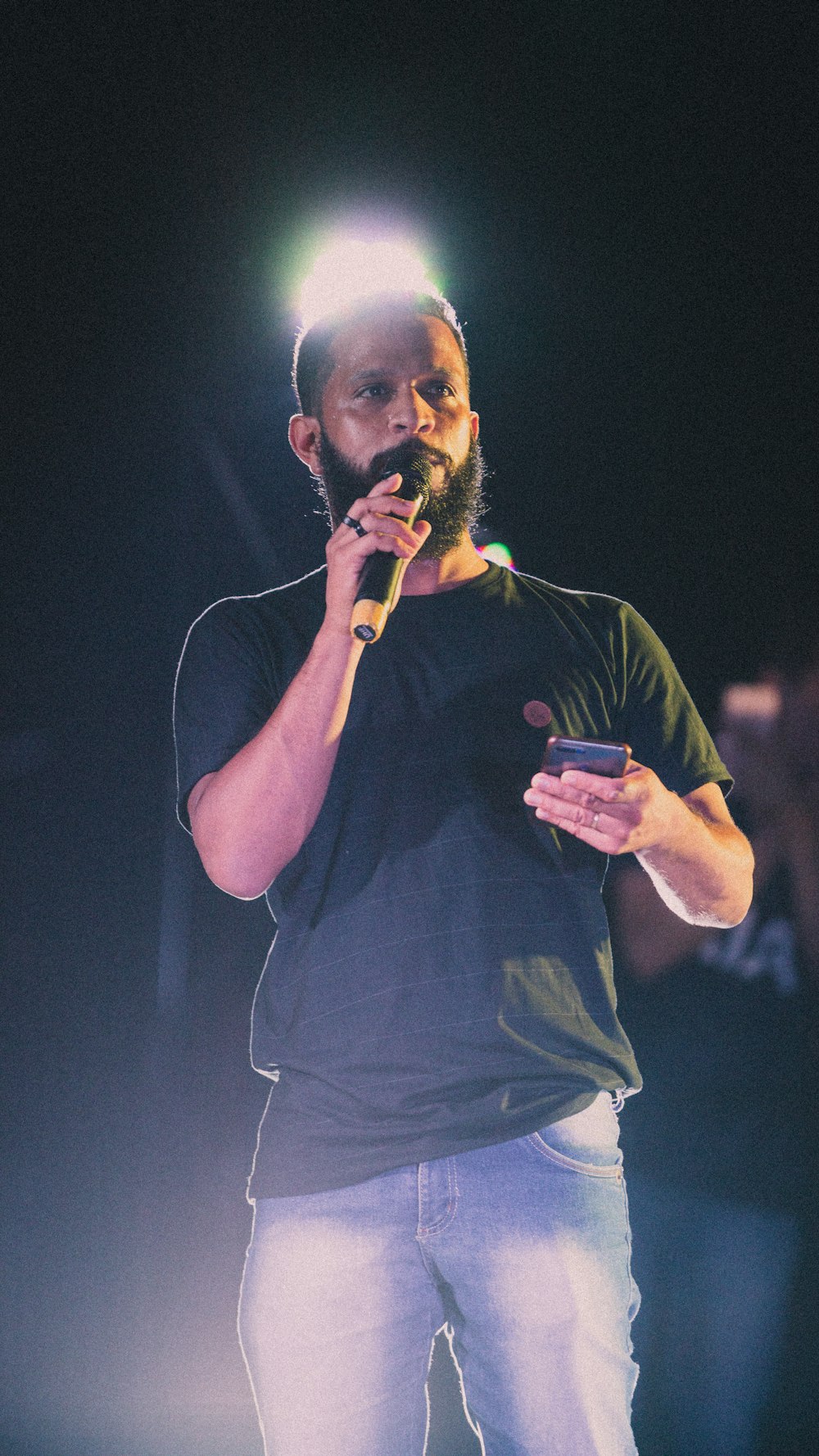 a bearded man holding a cell phone in his right hand