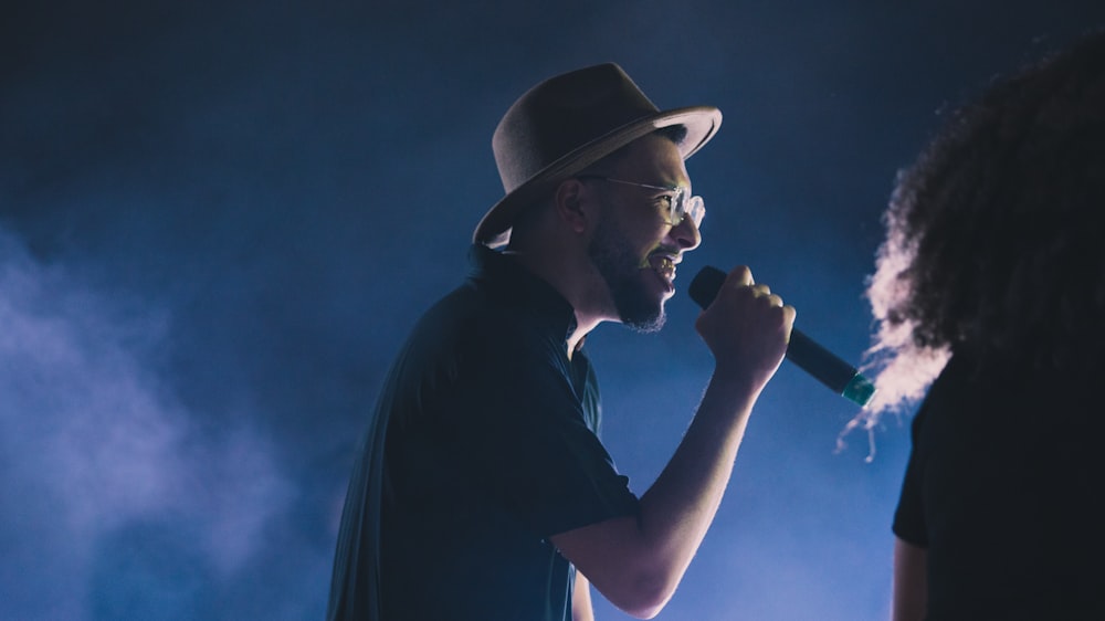 Un homme dans un fedora chante dans un micro