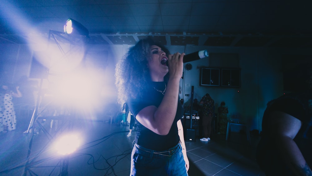 woman in black tank top singing on stage