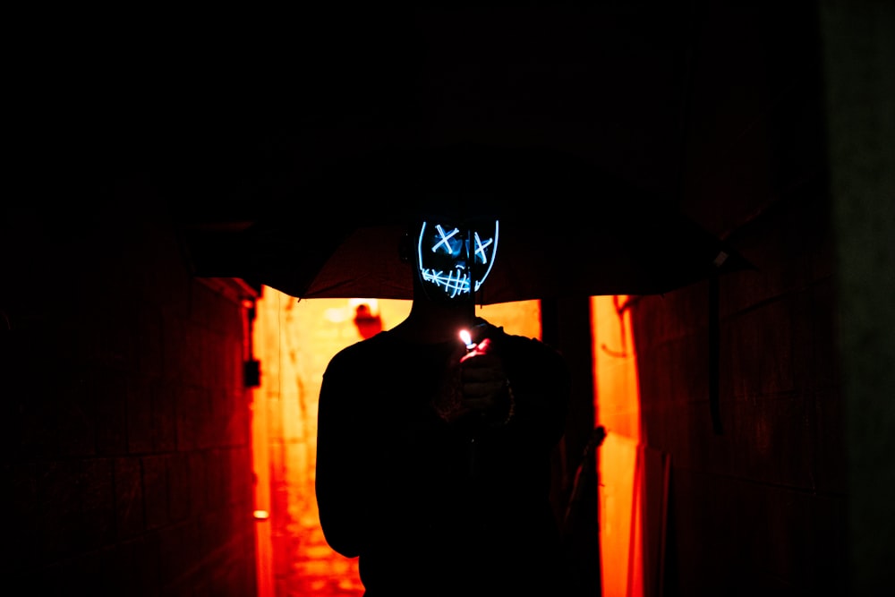 man in black hoodie standing near brown wall