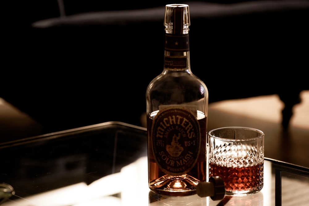 brown glass bottle beside clear drinking glass