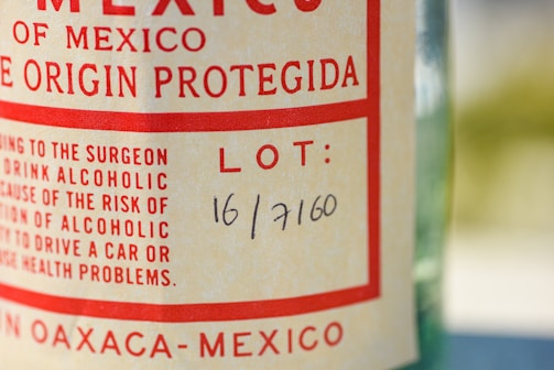 A close-up of a bottle label with text in red and black on a light background. The label includes wording related to Mexico and has a lot number handwritten as 16/7160.