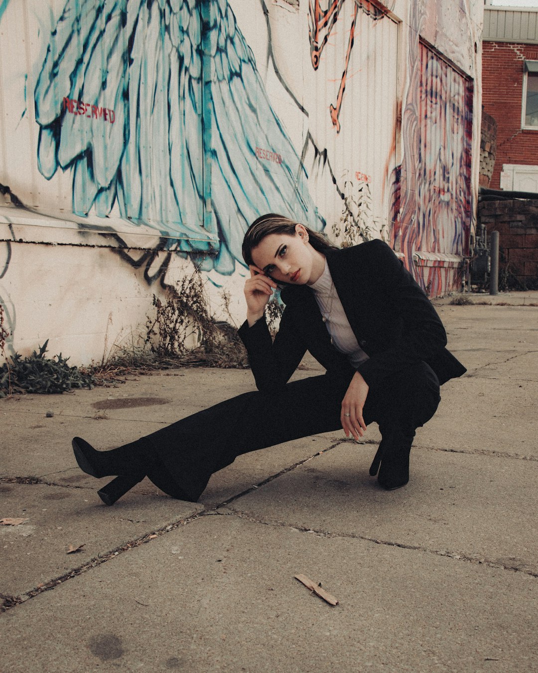 woman in black blazer and black pants sitting on concrete floor