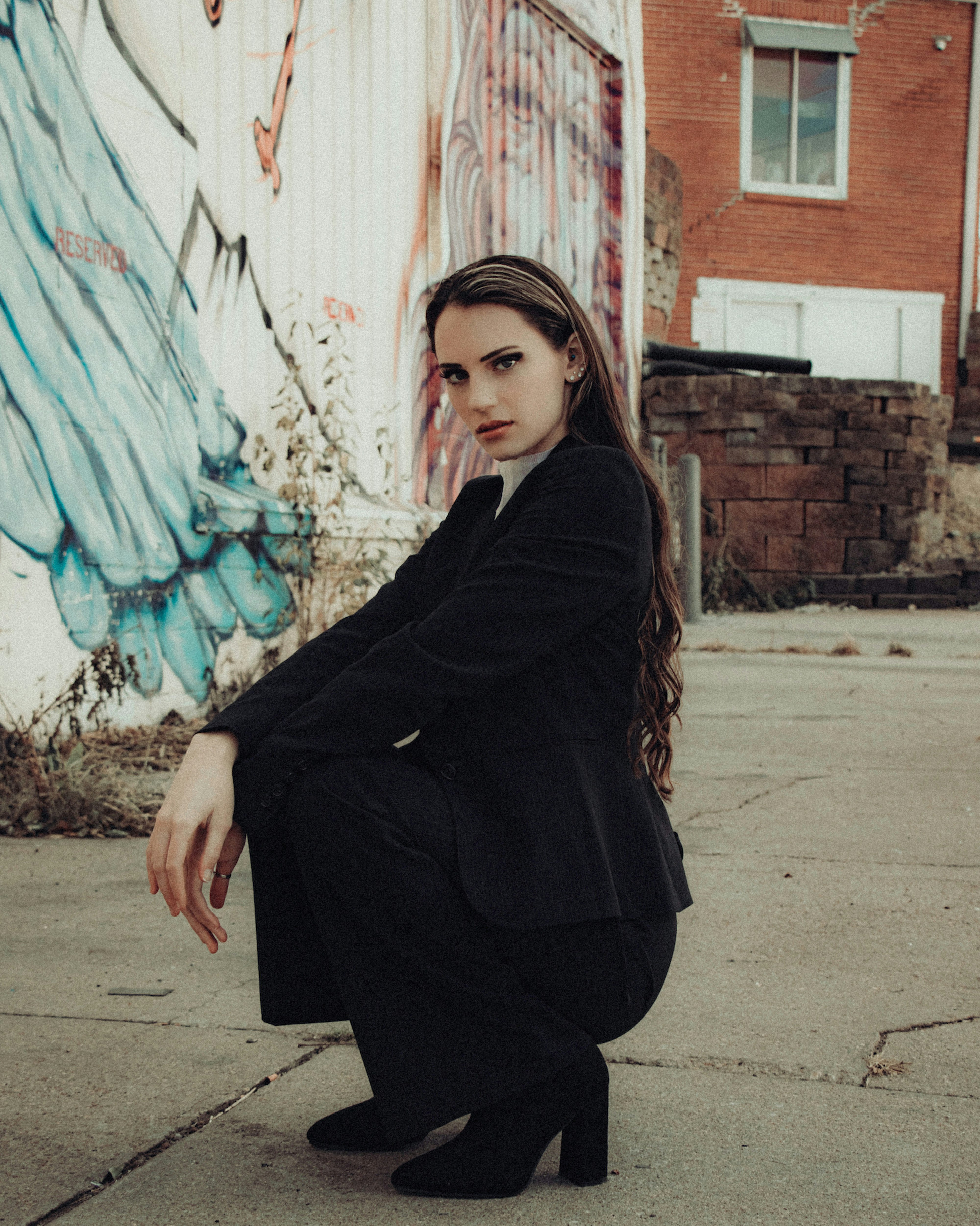 woman in black long sleeve dress standing near graffiti wall during daytime