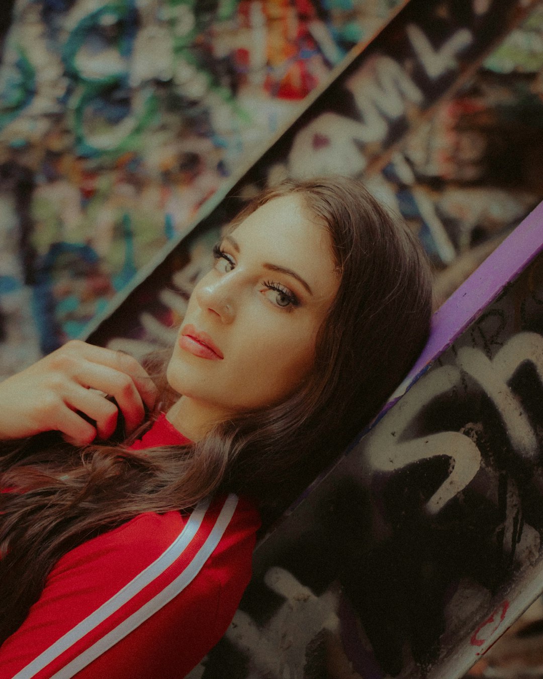 woman in black and red shirt leaning on wall with graffiti