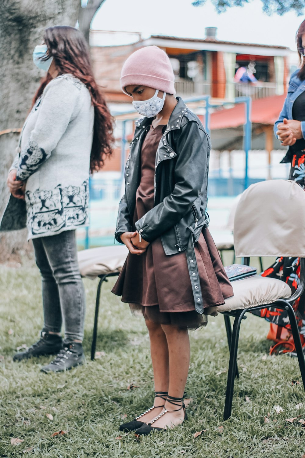 woman in black leather jacket and brown skirt holding brown leather sling bag