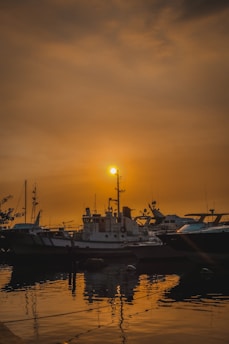 Aerial photo of a harbor with several boats docked, taken by a drone during sunset.