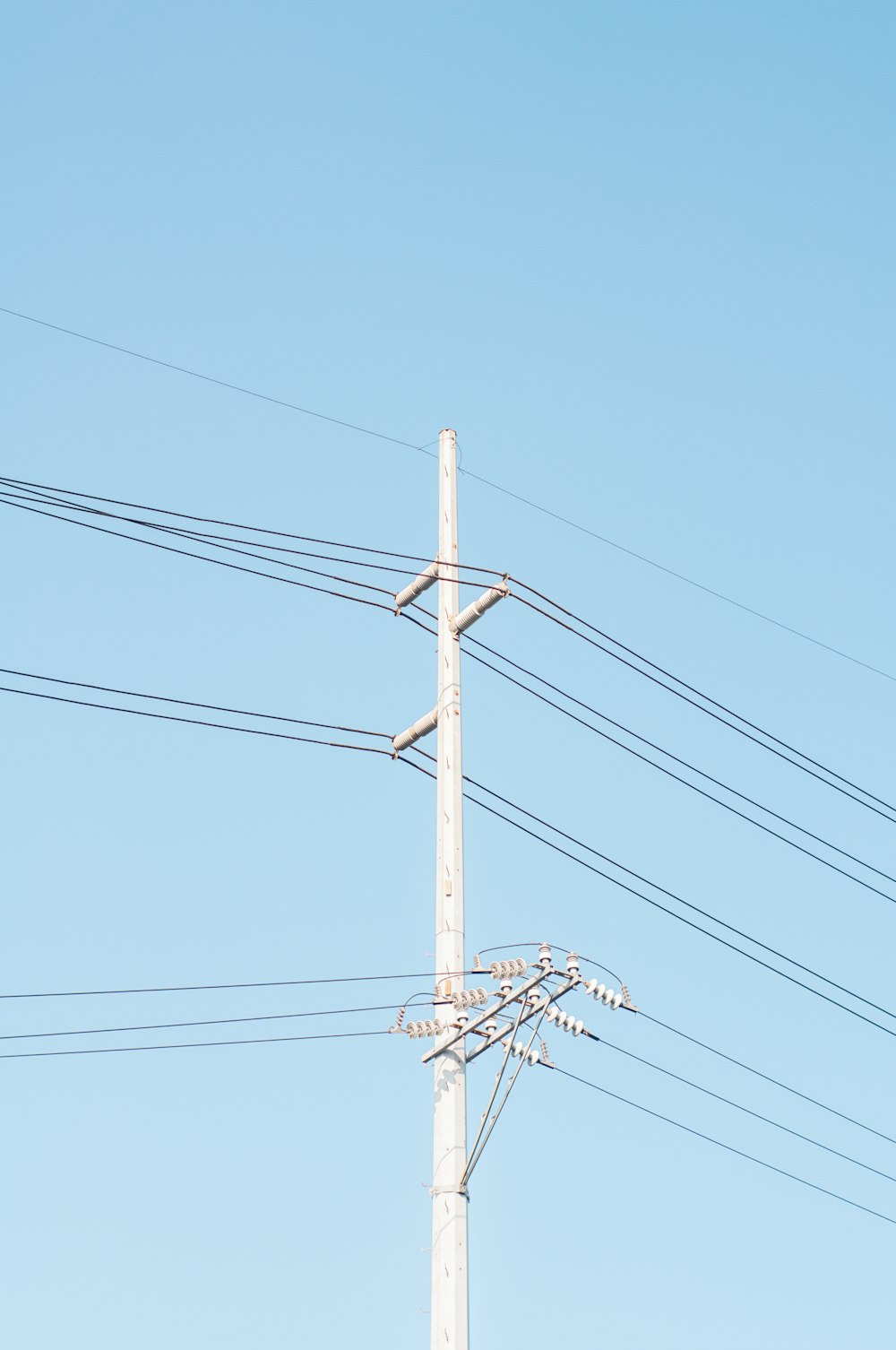 poteau électrique brun sous ciel bleu pendant la journée