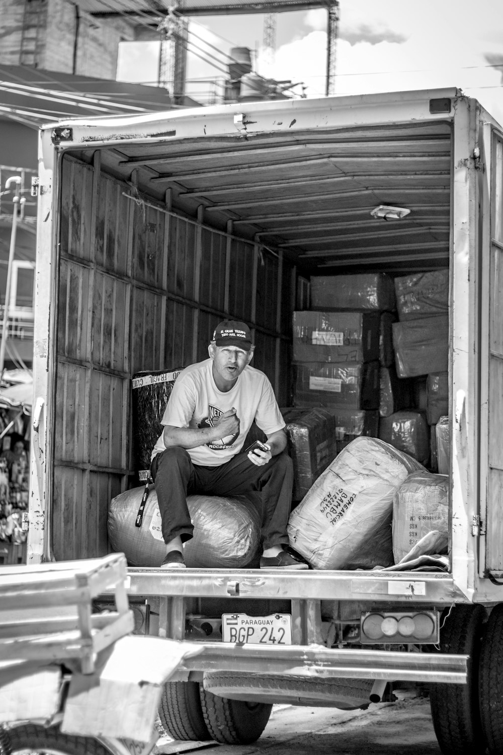 man in purple long sleeve shirt sitting on wooden crate