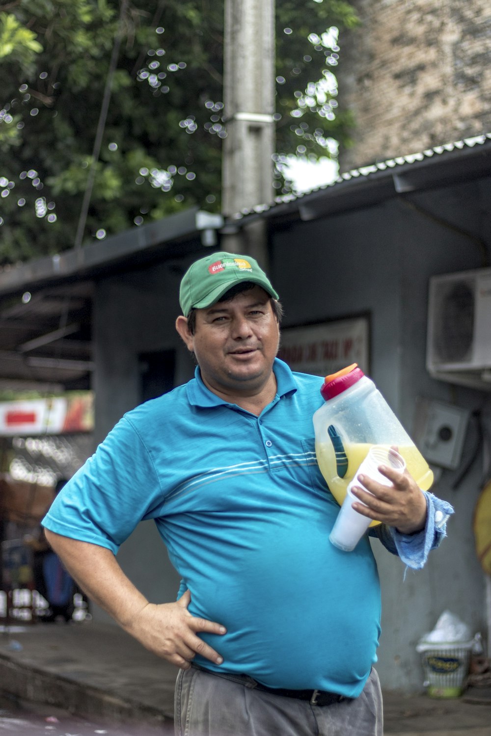 man in blue polo shirt holding white and green plastic bottle